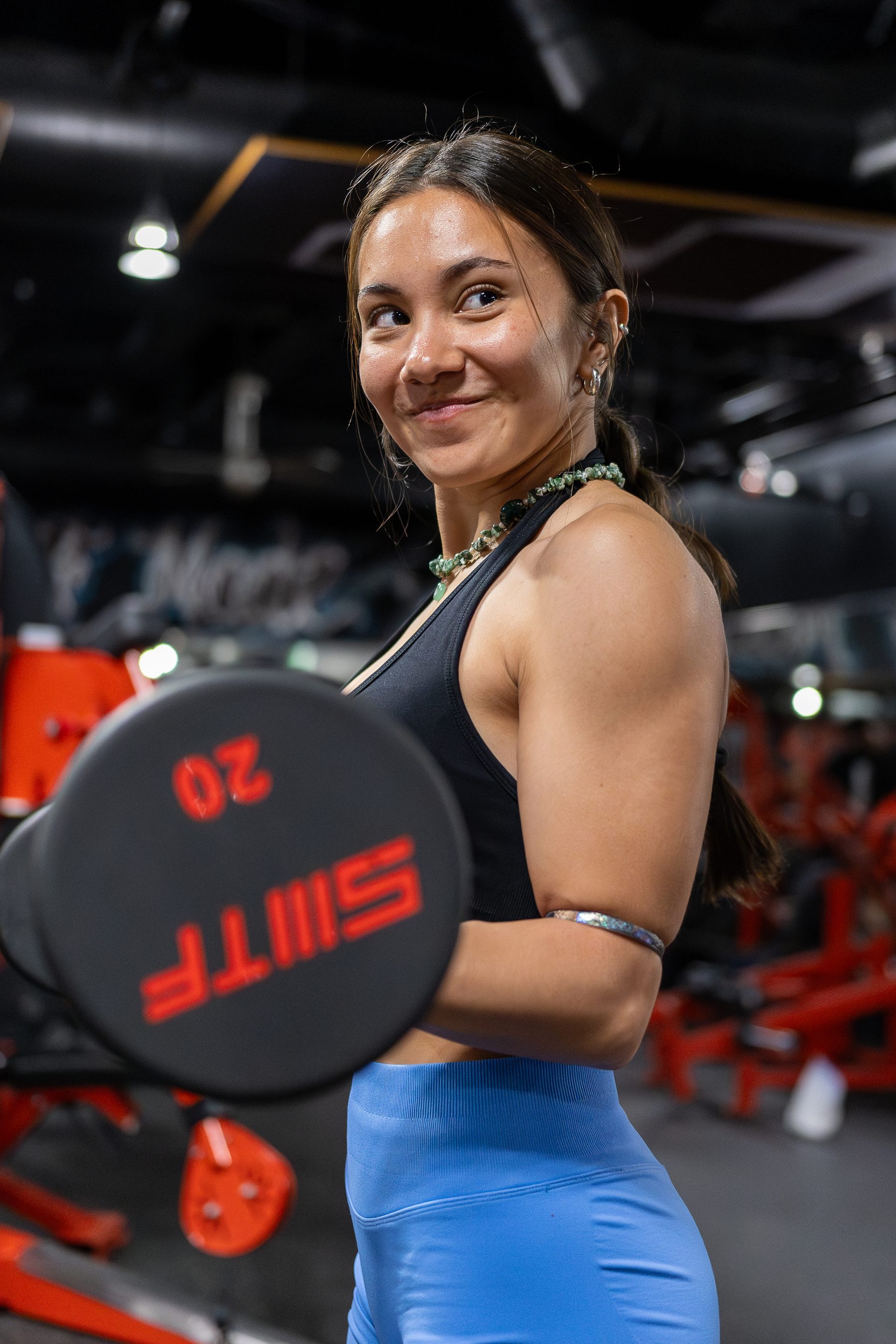Member with a dumbbell and a smile at Legacy Del Mar